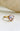 Meliora powder blush sapphire engagement ring featuring a rare 2.7ct oval natural sapphire in 14k yellow gold with diamond accents.