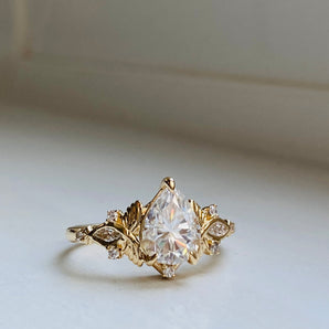 romantic gold engagement ring with sparkling pear cut diamond center and accented delicate gold and diamond butterflies on the size. Medium size engagement ring 
