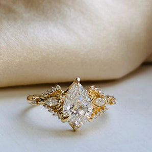 Gold ring with a pear-shaped diamond tapered by delicate gold butterfly wings design, encrusted with small diamonds in  different shape. Inspired by Ginkgo leaves