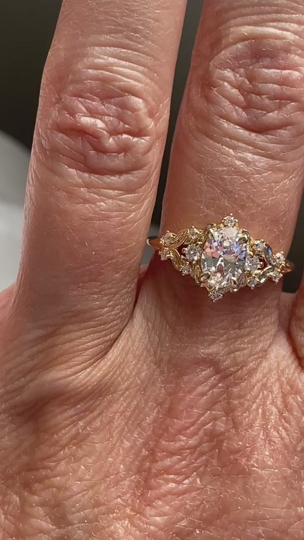 Romantic antique-inspired white sapphire ring with delicate floral gold accents
Elegant alternative engagement ring featuring a natural oval white sapphire in an ornate gold setting